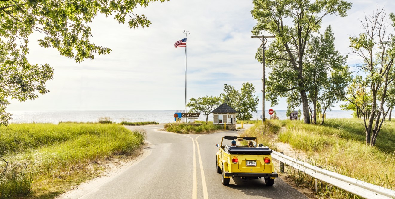 yellow convertible driving into oval beach
